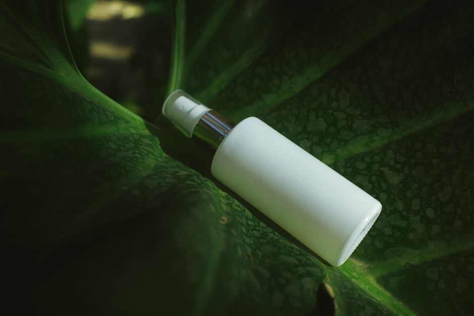 Close-up of a white spray bottle on a textured green leaf, highlighting eco-friendly packaging.